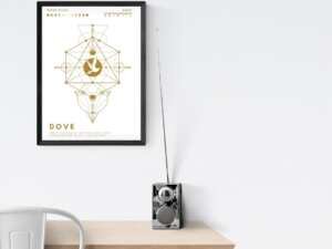 A framed print of a dove crystal grid hangs on a white wall above a wooden desk with a radio on it. The grid features a geometric design with a dove in the center. Text below the dove reads "Dove: Purity, Gentleness, Devotion, Hope, Love, Communication, Peace, and Sacrifice."